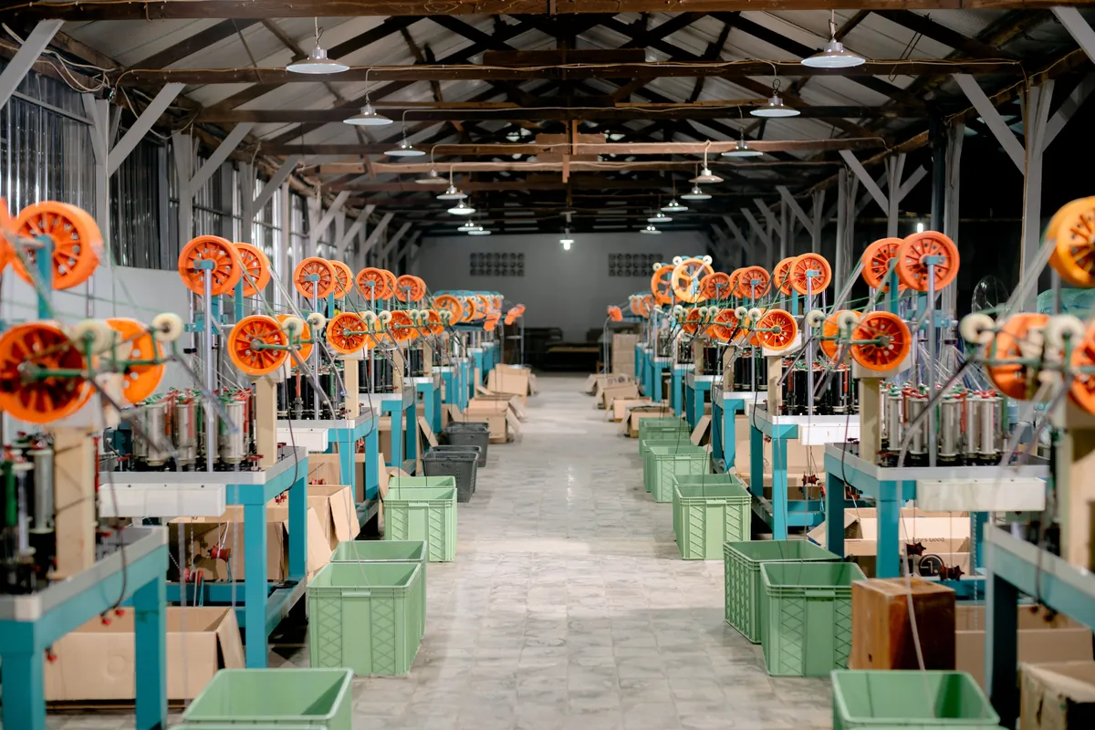 Un plancher d'atelier: deux rangées de machines de production et des bacs de pièces entre elles.